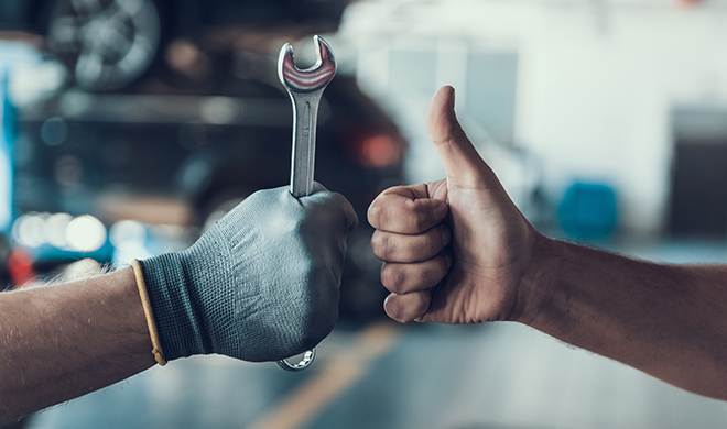 Close-up Thumb Up and Mechanics Hand with Tool. Automobile Master Wearing Gloves Showing Positive Gesture after Finishing Work. Technic occupation. Automobile Repair Service Concept.